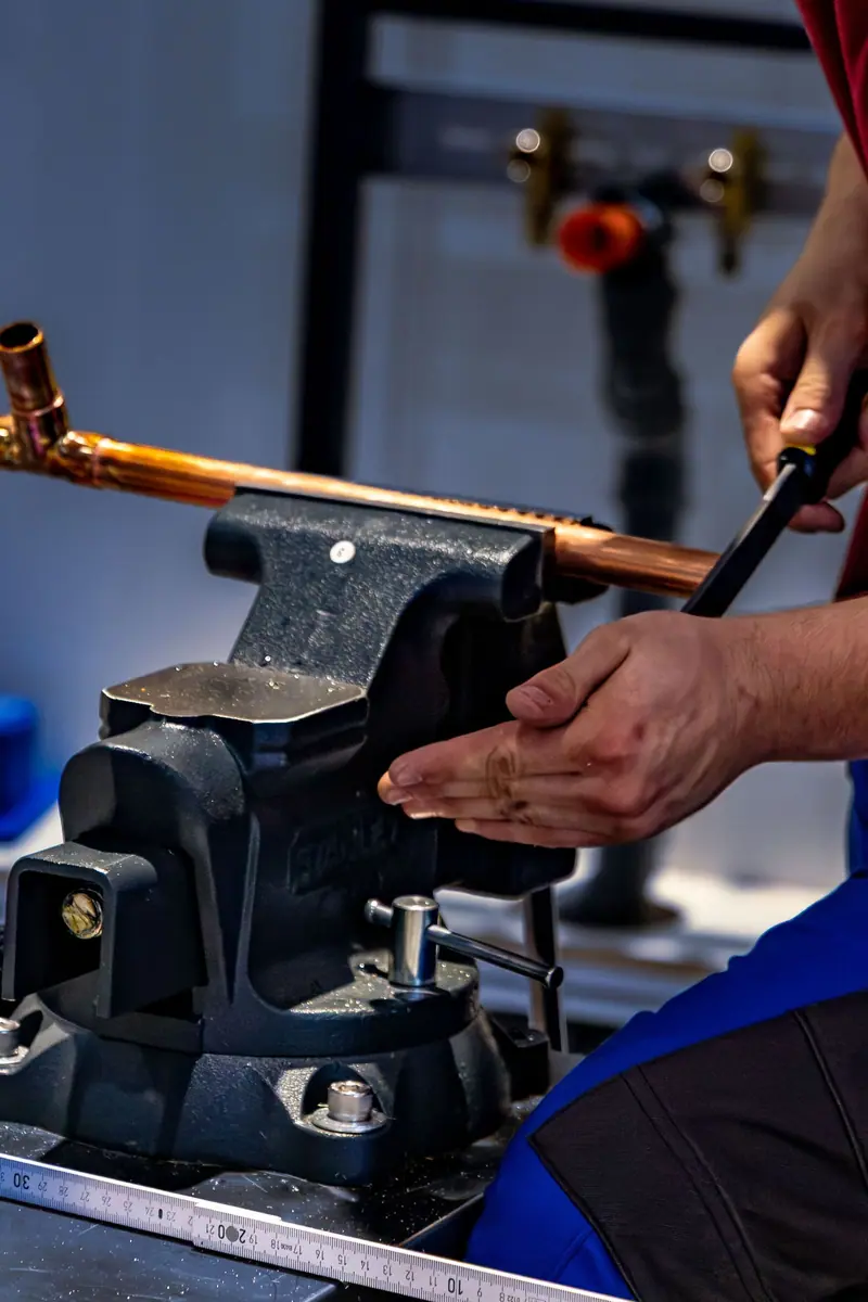 Plumber bending new copper pipe in a vise