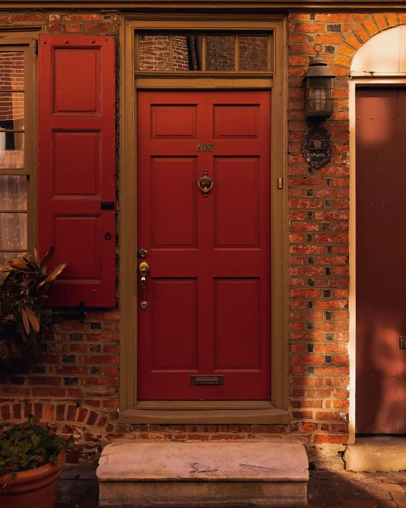 Brick Philadelphia rowhome entrance with a red door